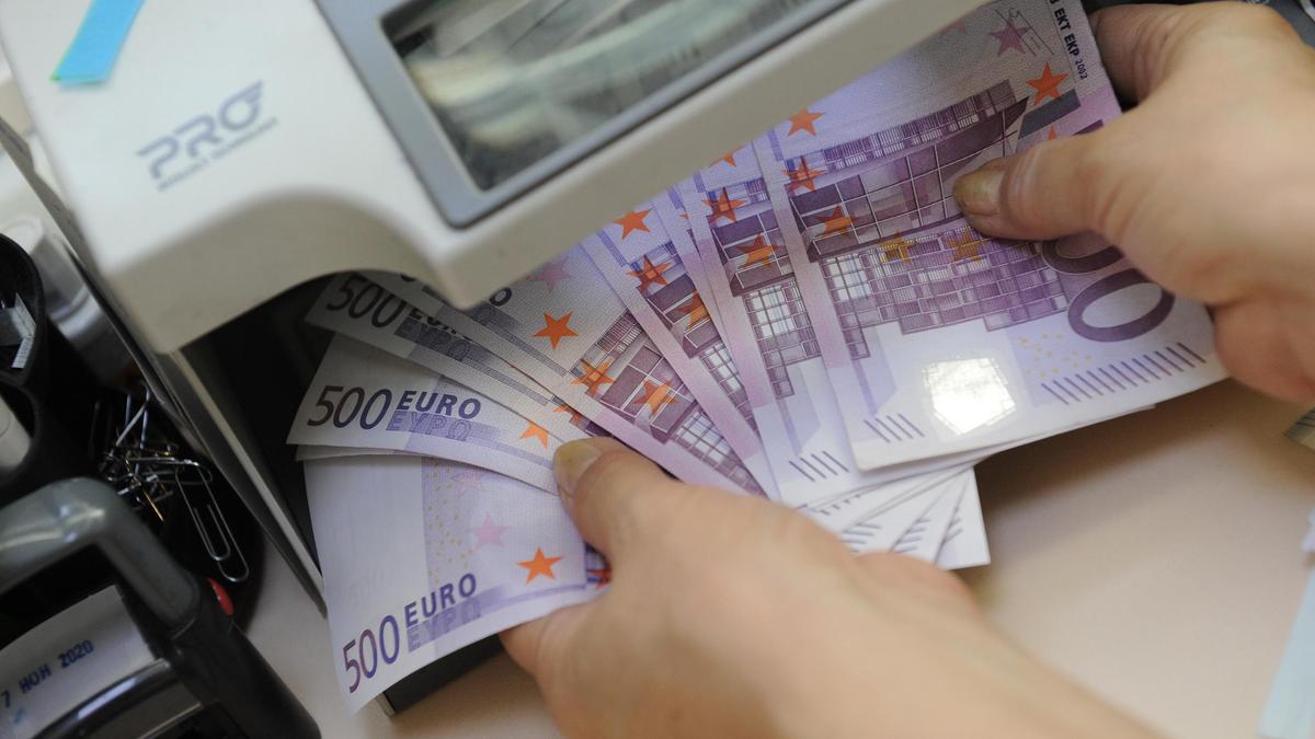 Кассир проверяет купюры евро на подлинность Кассир проверяет купюры евро на подлинность