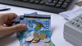Женщина кладет деньги на стол рядом с кассовым аппаратом
